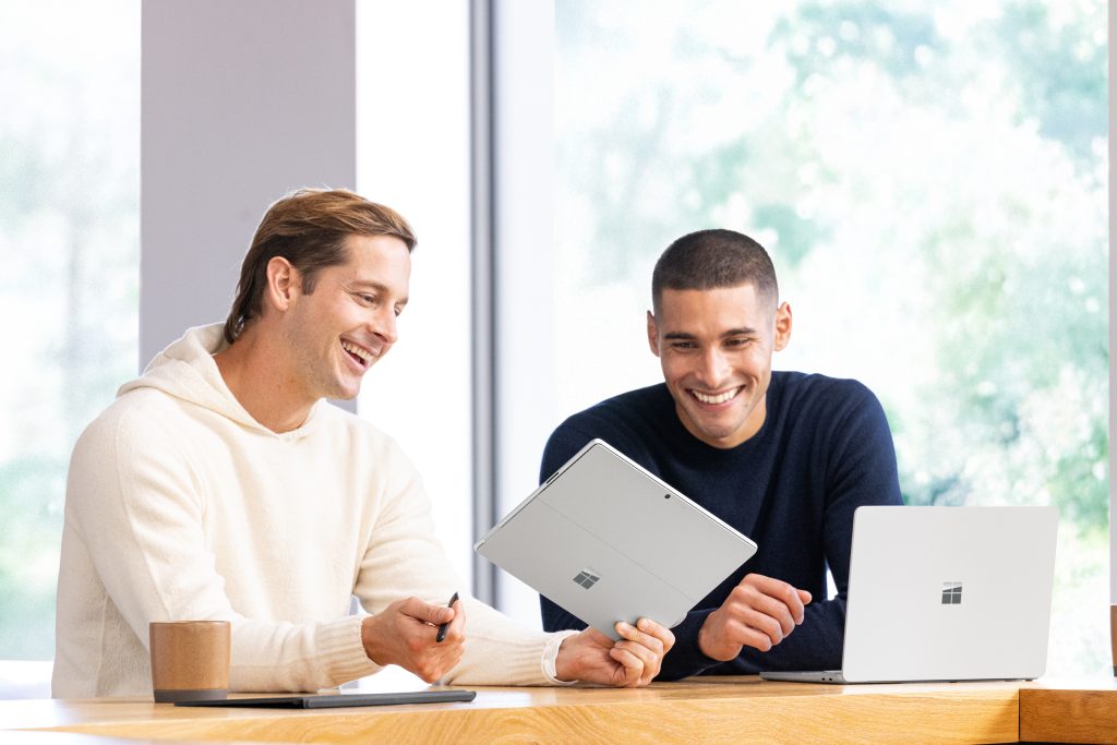 Two people sitting at cafe working on Surface Laptop and Surface Pro